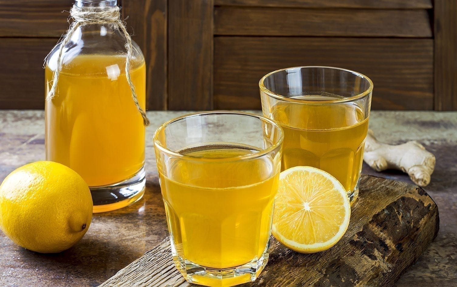 A glass of orange juice next to a cup of beer on a table